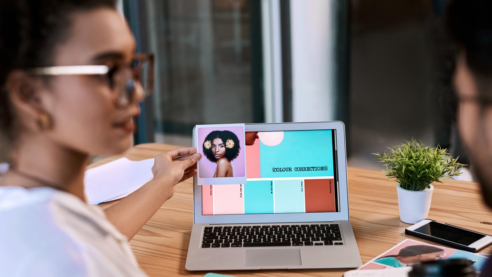 a man and a woman looking at a color chart on a laptop on a table