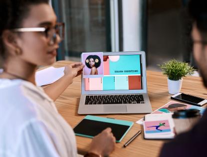 a man and a woman looking at a color chart on a laptop on a table