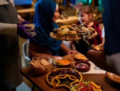 In a heartwarming scene a professional chef serves Mediterranean cuisine to a table of male and female guests 