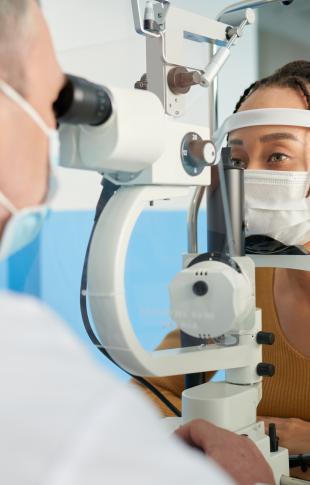 a doctor giving an eye exam to a masked woman