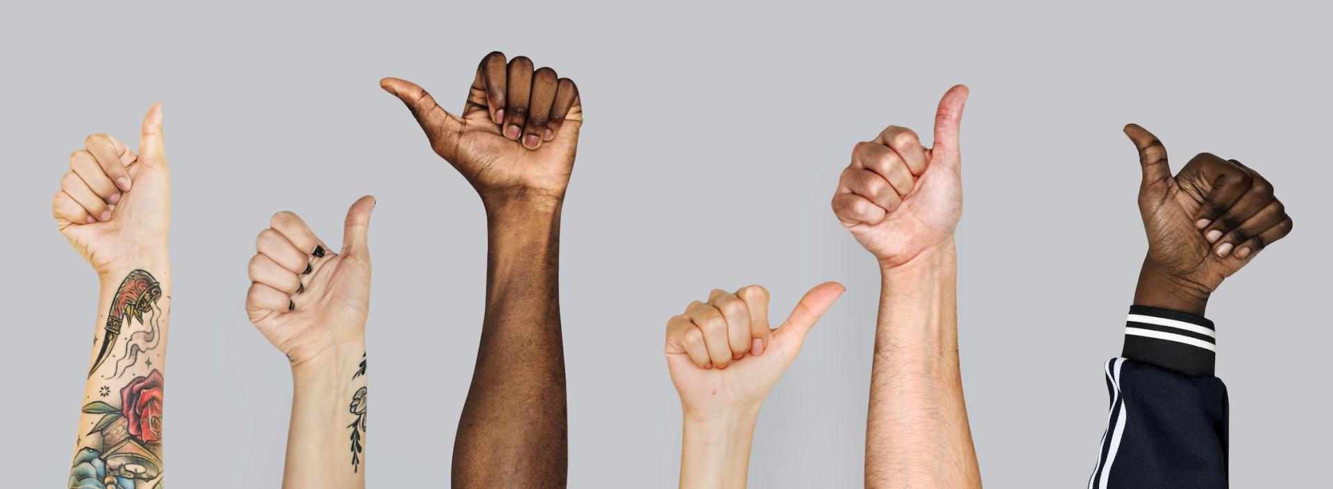 Diverse workers giving the thumbs up sign to deal with positive results